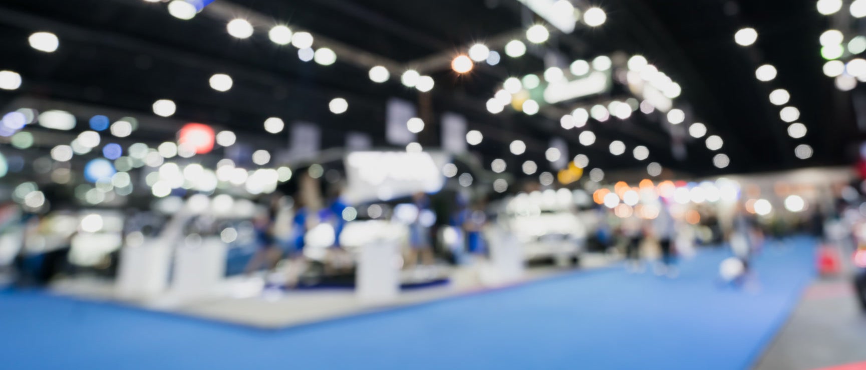 Blurred, defocused background of public event exhibition hall showing cars and automobiles, business commercial event concept